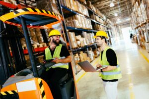 Warehouse workers working together with forklift loader